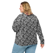 Looking at the back view of a woman wearing the unisex needlepoint-look bomber jacket with a modern squares  pattern in shades of black, white and grey. The blonde woman is also wearing light colored jeans.